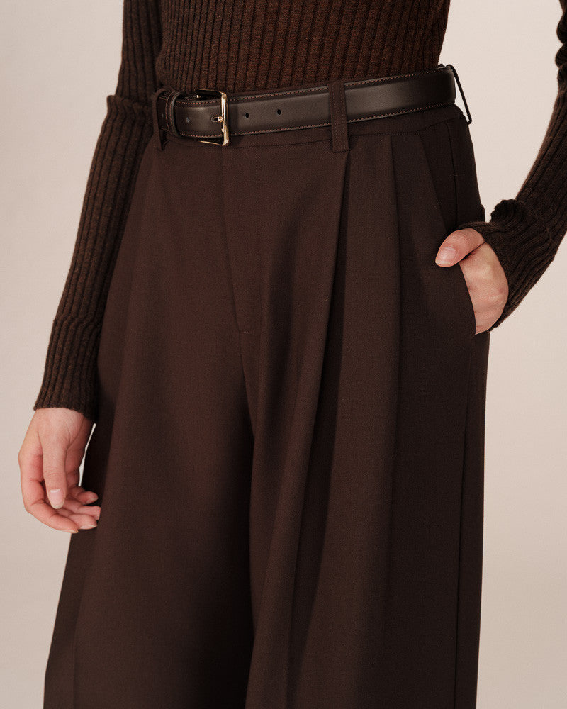Brown pleated skirt worn with a matching sweater against a neutral background