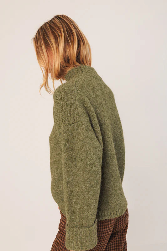 Person wearing a green sweater against a white background