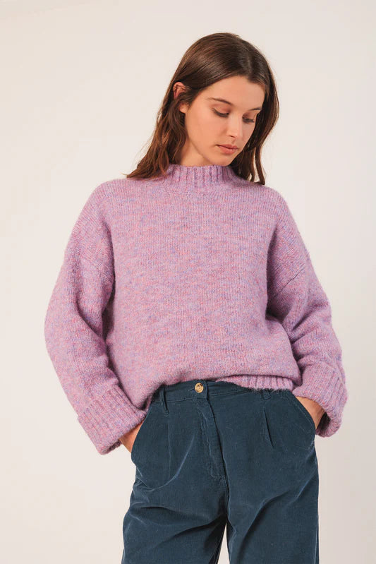 Person wearing a purple sweater and blue pants on a white background