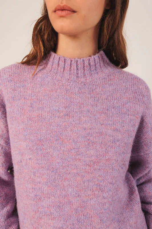 Close-up of a person wearing a textured purple sweater against a plain background