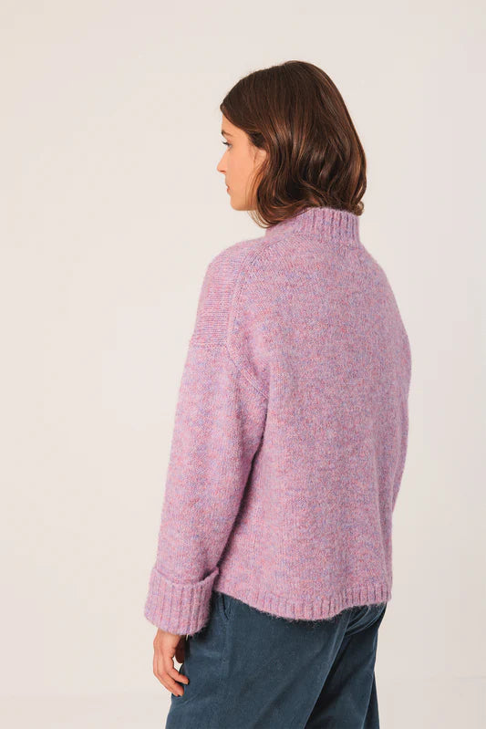 Person wearing a pink knitted sweater against a white background