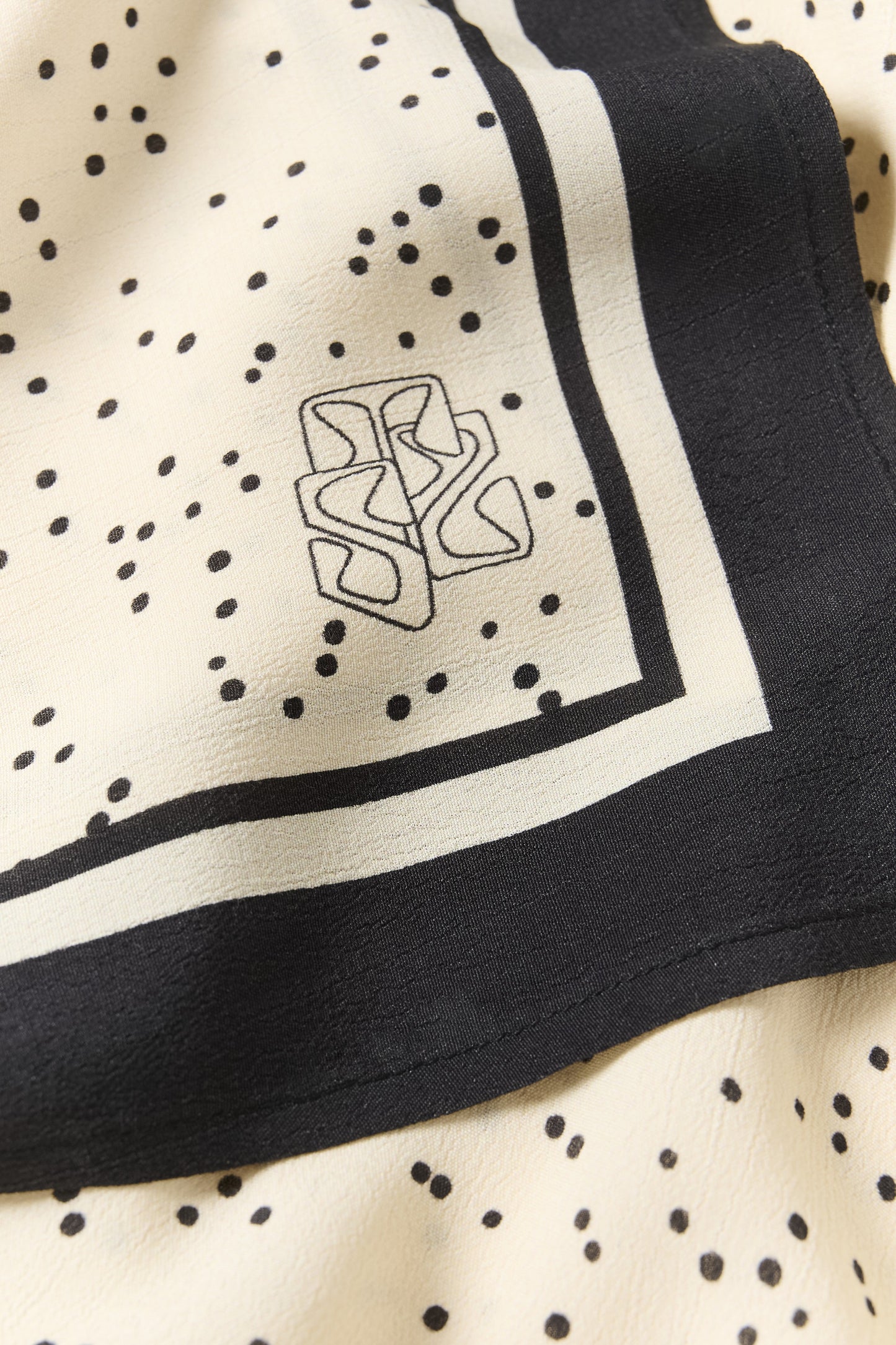 Black and white polka dot fabric with a logo in the corner