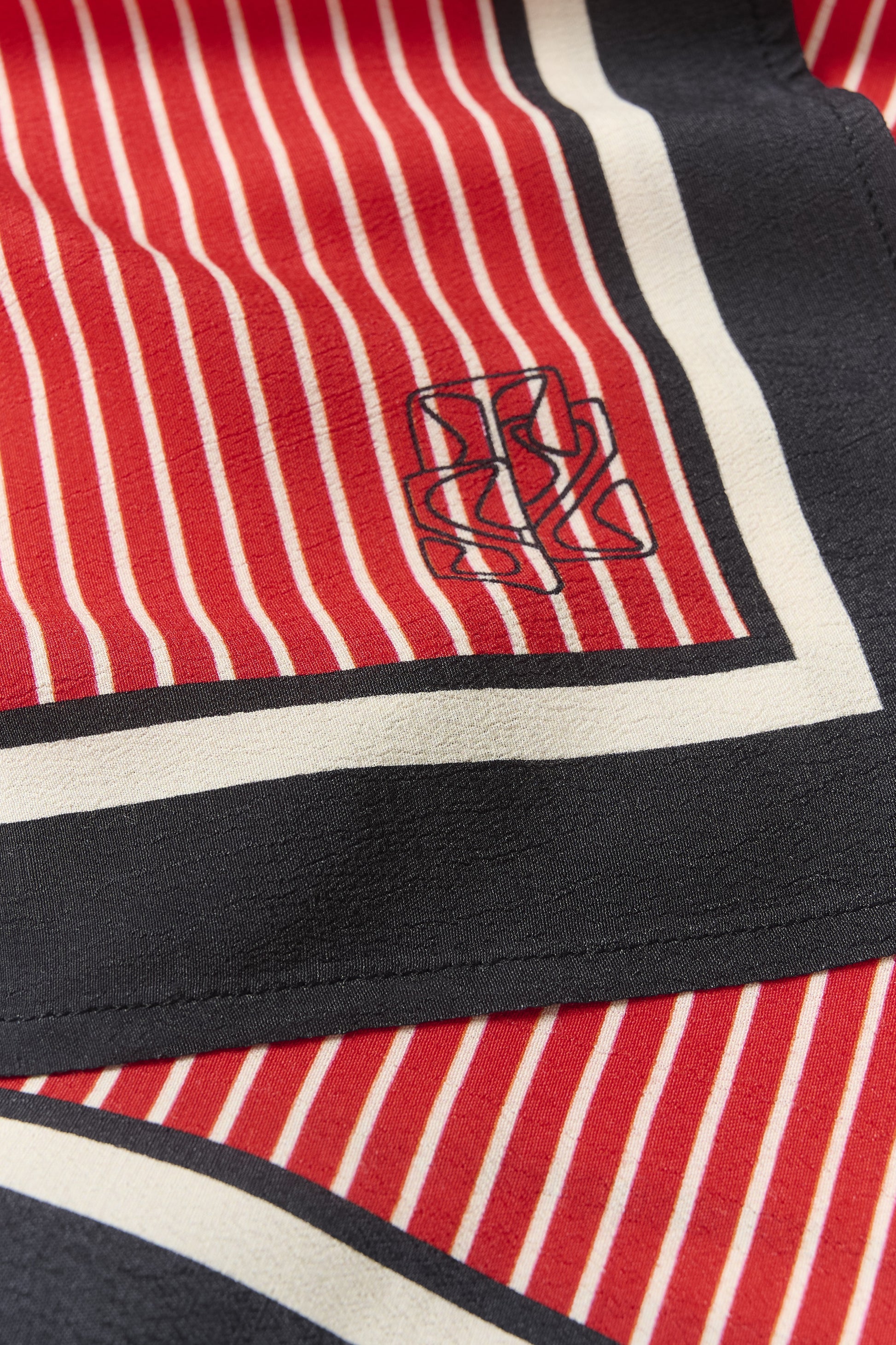 Close-up of a red and black striped fabric with a logo in the center.