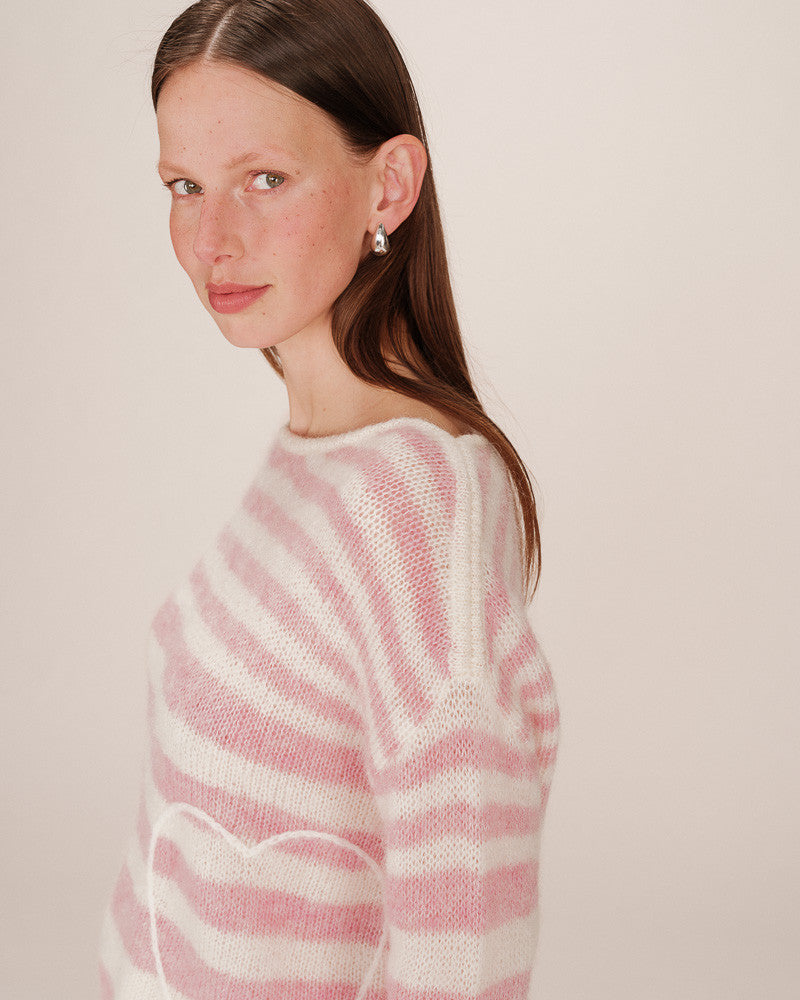 Woman wearing a pink and white striped sweater against a plain background