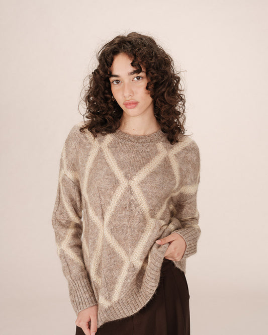 Woman wearing a patterned sweater against a plain background