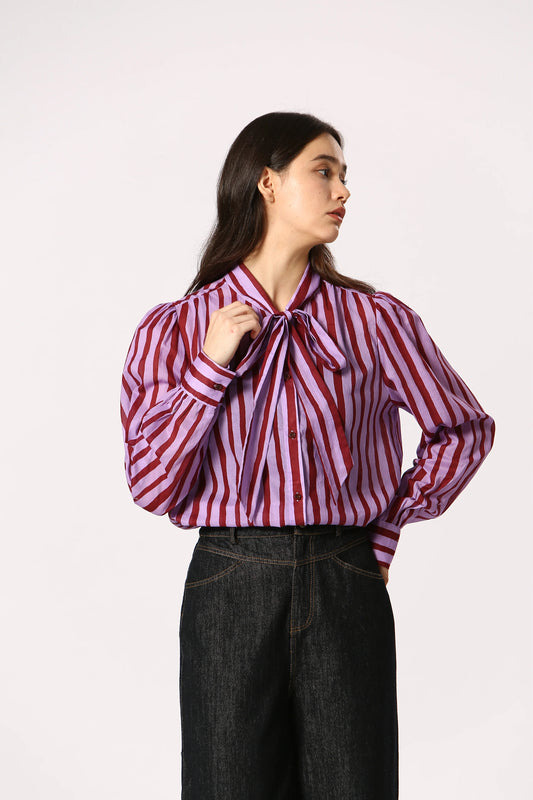 Woman wearing a purple and maroon striped shirt with a bow tie on a white background