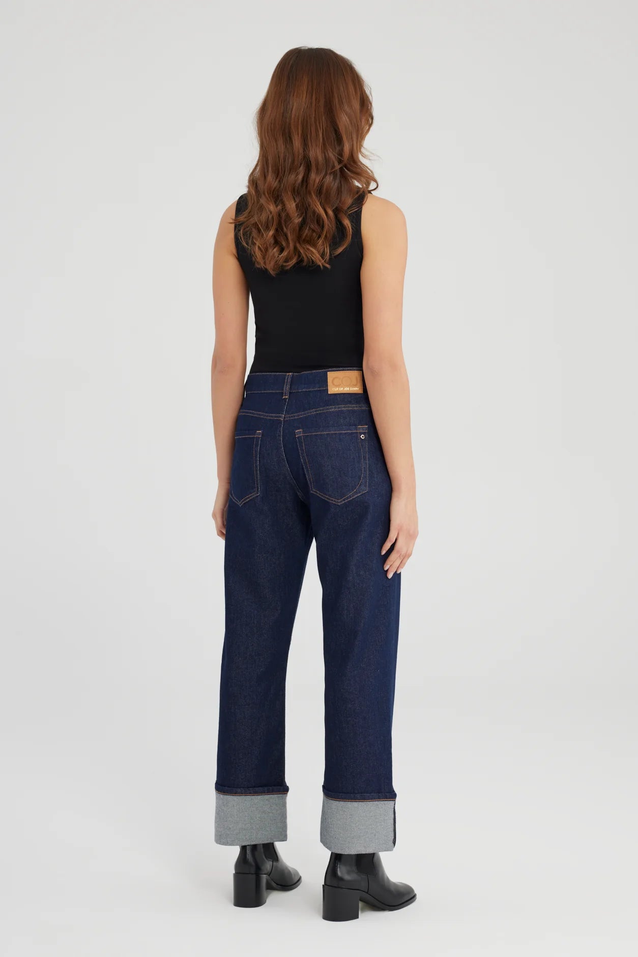 Person wearing dark blue jeans and black top on a white background