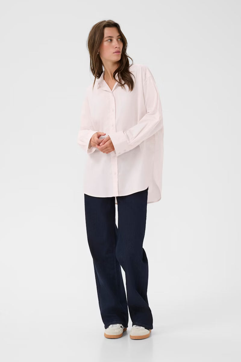 Woman wearing a light pink blouse and dark blue pants on a white background