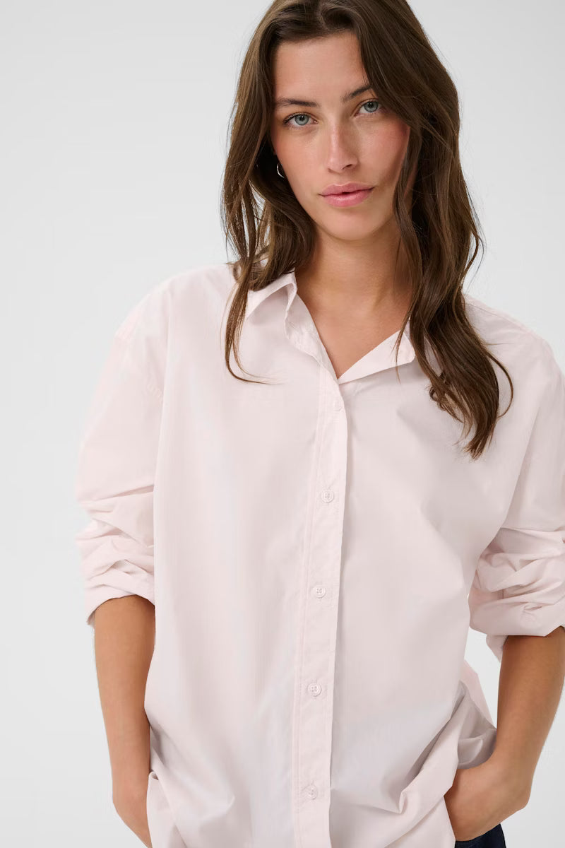 Woman wearing a light pink shirt against a white background