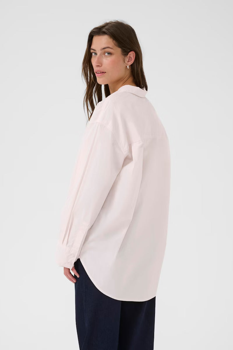 Woman wearing a light pink blouse and dark pants on a white background