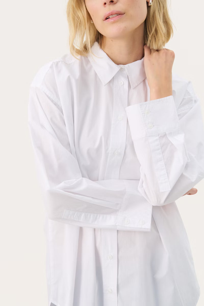 Person wearing a white shirt against a plain background