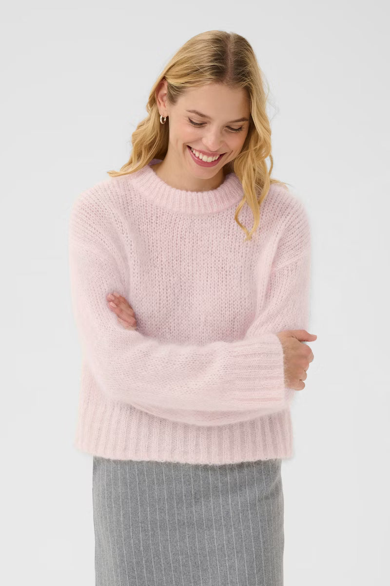 Woman wearing a pink sweater against a white background
