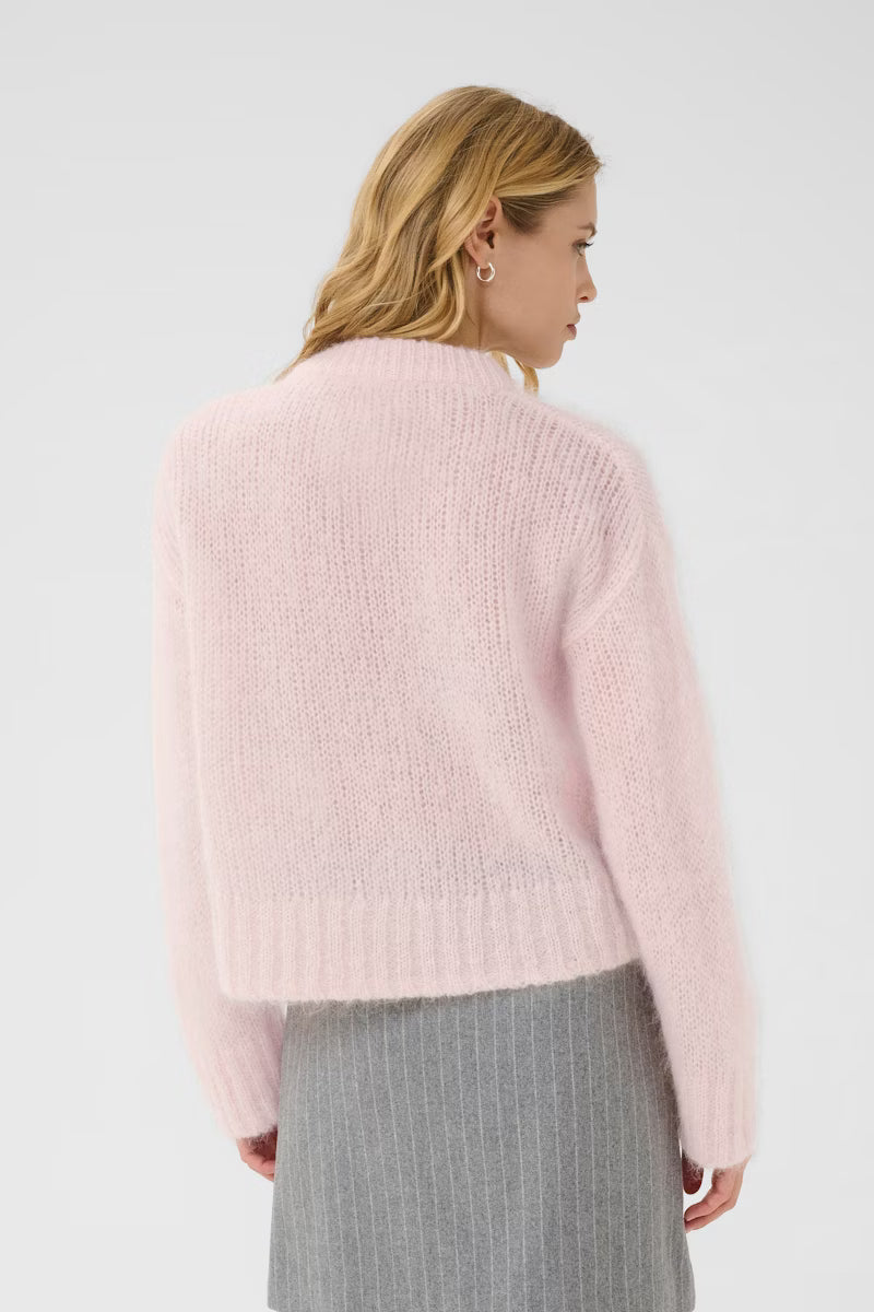 Woman wearing a light pink sweater against a white background