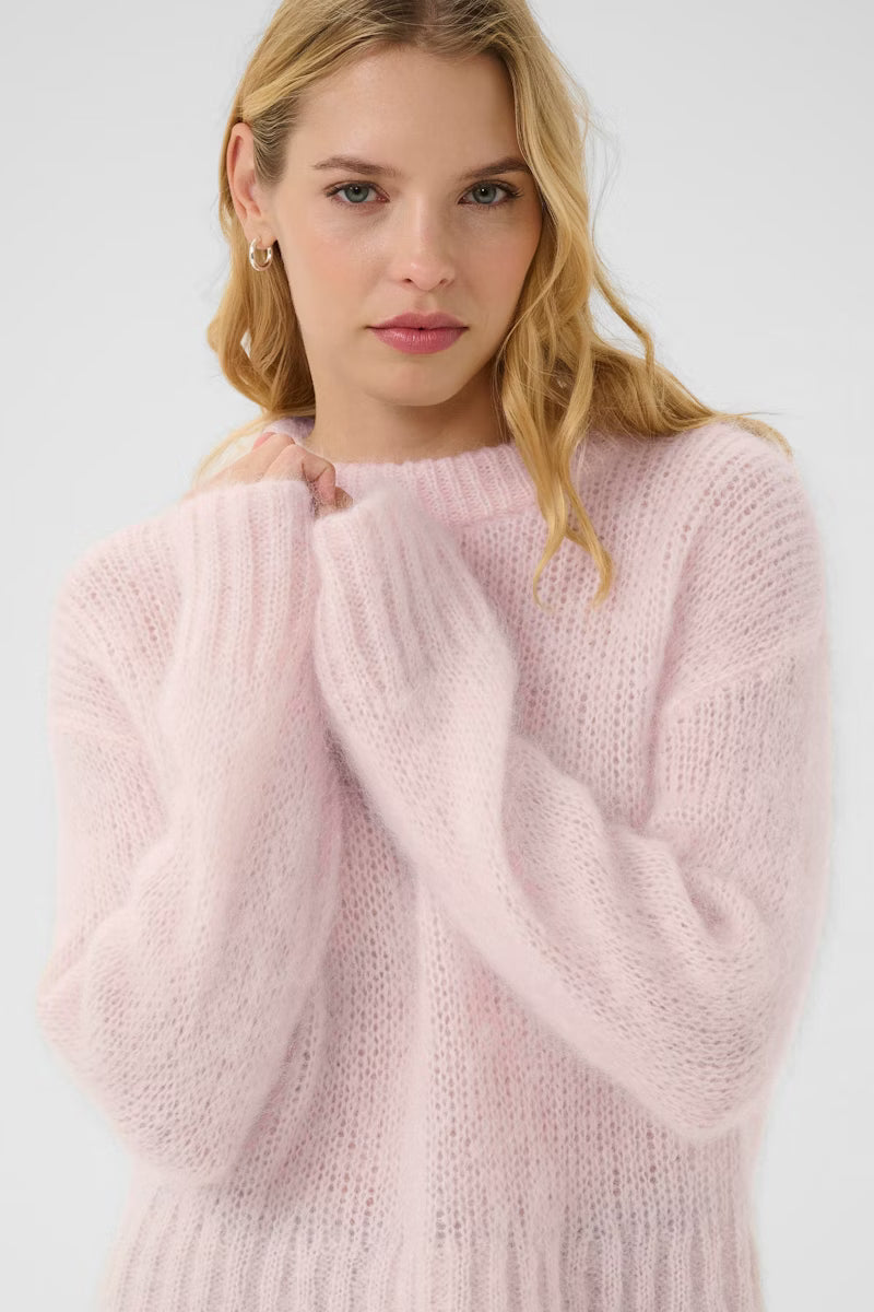 Woman wearing a light pink sweater against a white background