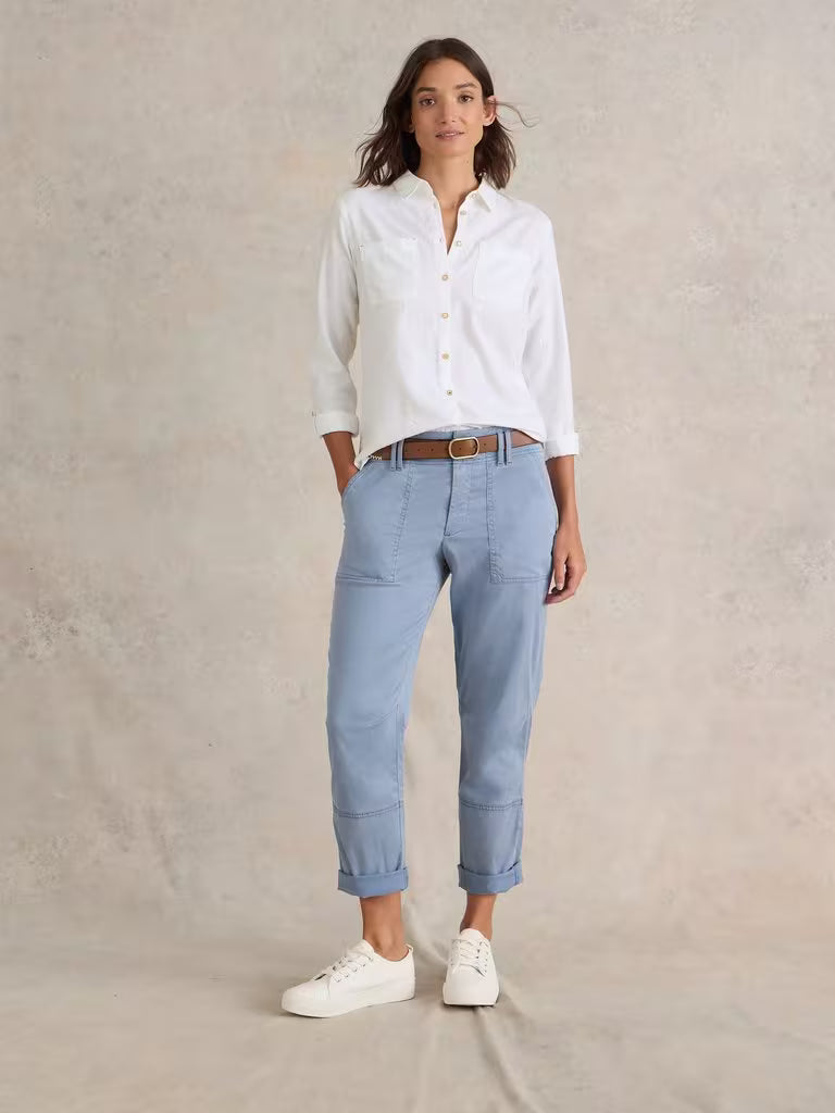 Woman wearing a white shirt and light blue pants on a beige background