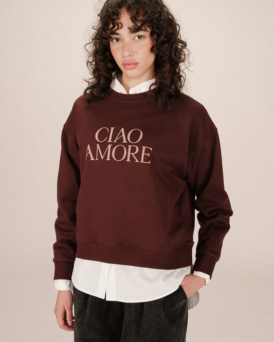 Person wearing a maroon sweatshirt with 'CIAO AMORE' text on a beige background