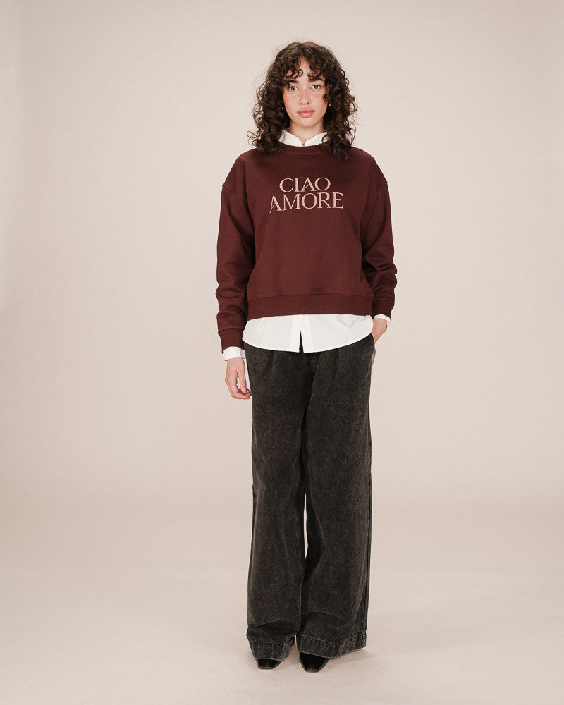 Person wearing a burgundy sweater with 'CIAO AMORE' text on a plain background