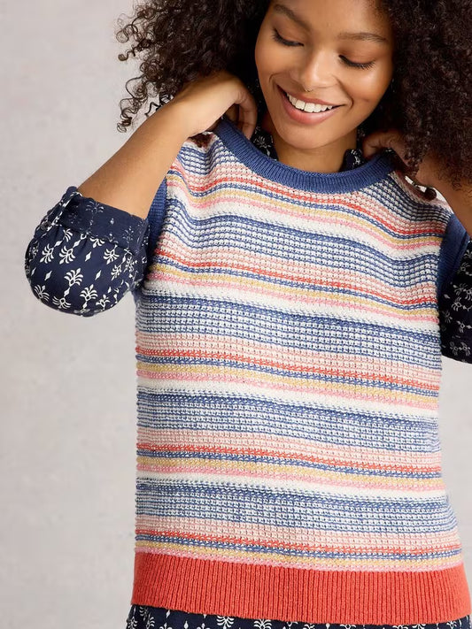 Person wearing a colorful striped sweater with patterned sleeves on a plain background
