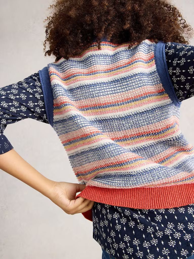 Person wearing a colorful striped sweater with a neutral background