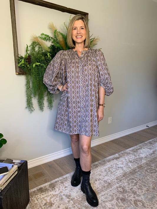 This Buttoned dress by the Korner features a timeless design with a classic round neckline and flattering long puffed sleeves that showcase the flared cut of the skirt, creating a flattering and comfortable silhouette. The geometric pattern in hues of purple with ochre accents is perfect for an autumnal look. lemon cyprus boutique