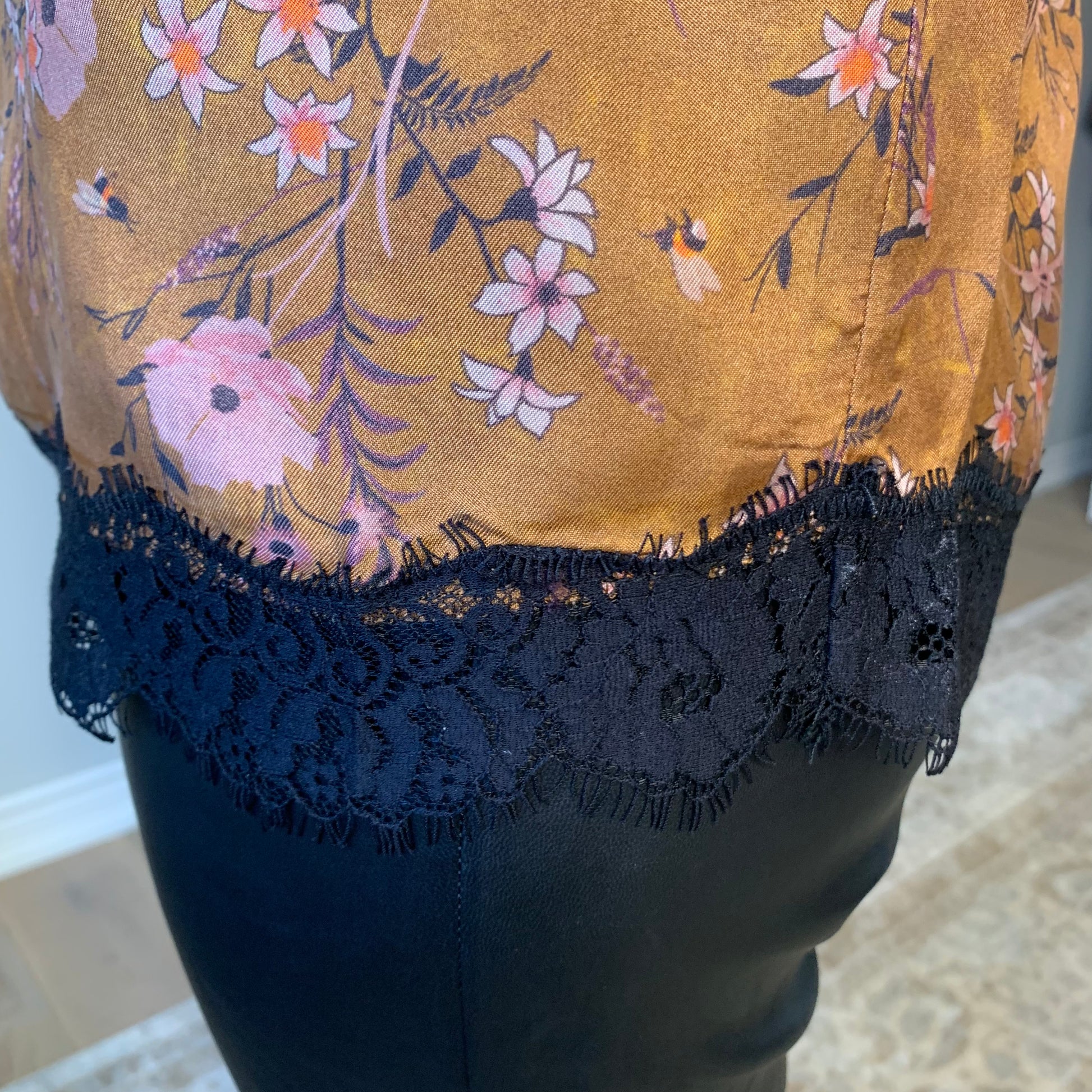 This Floral Camisole by the Korner presents a straight cut with black lace trimming around the hemline. An eye-catching, soft floral pattern in purple and pinks is set against a deep, velvety cinnamon hue, providing a luxuriously matte silk like finish. lemon cyprus boutique