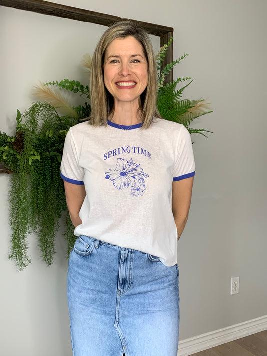 Introducing the Spring Time Graphic Tee by The Korner! This short-sleeved tee in white with blue trim on the arms and collar is a must-have for the season. With "spring time" and a floral picture, it's both stylish and comfy for everyday wear. Get yours now and embrace spring in style!