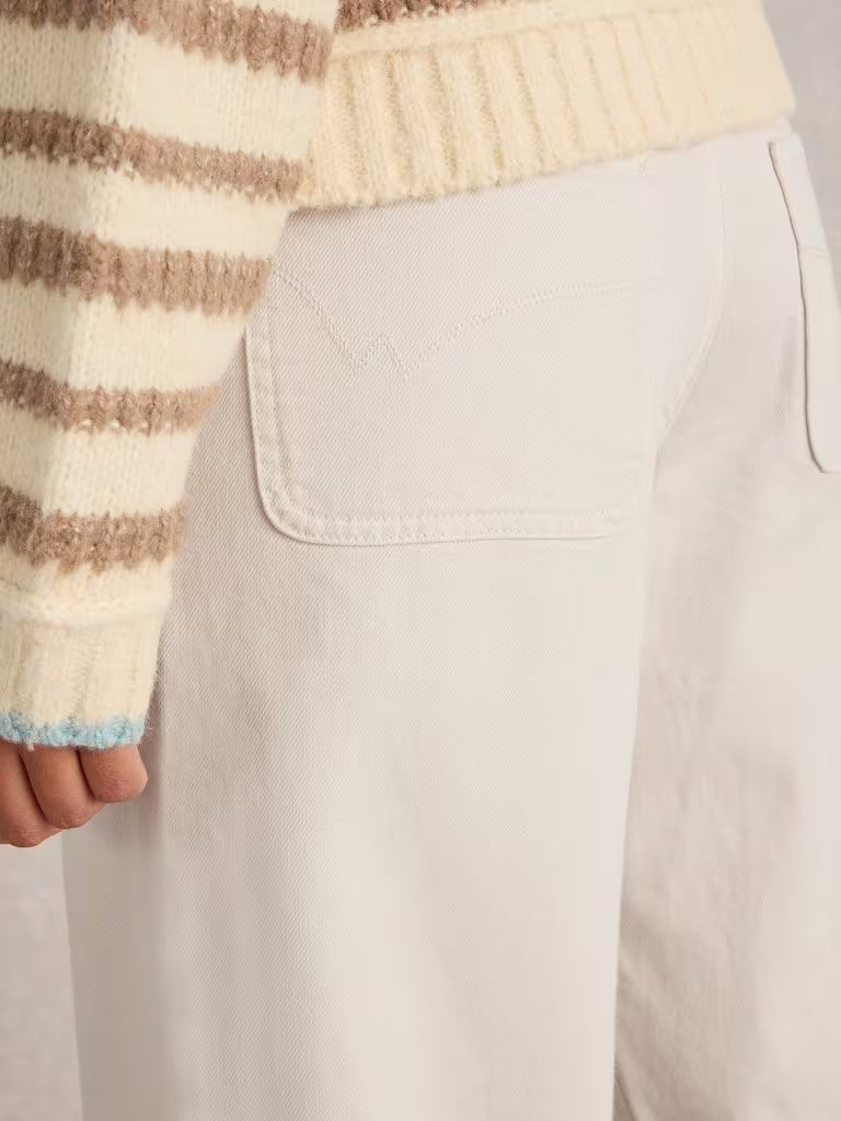 Close-up of a person wearing a striped sweater and beige pants.