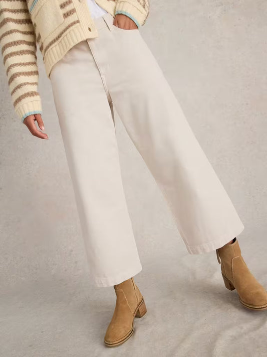 Person wearing beige pants and brown boots on a neutral background