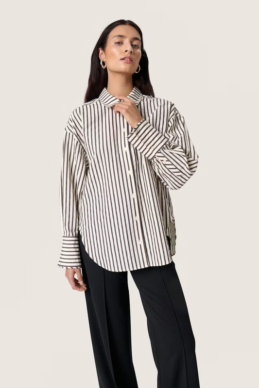 Woman wearing a brown and white striped shirt against a beige background