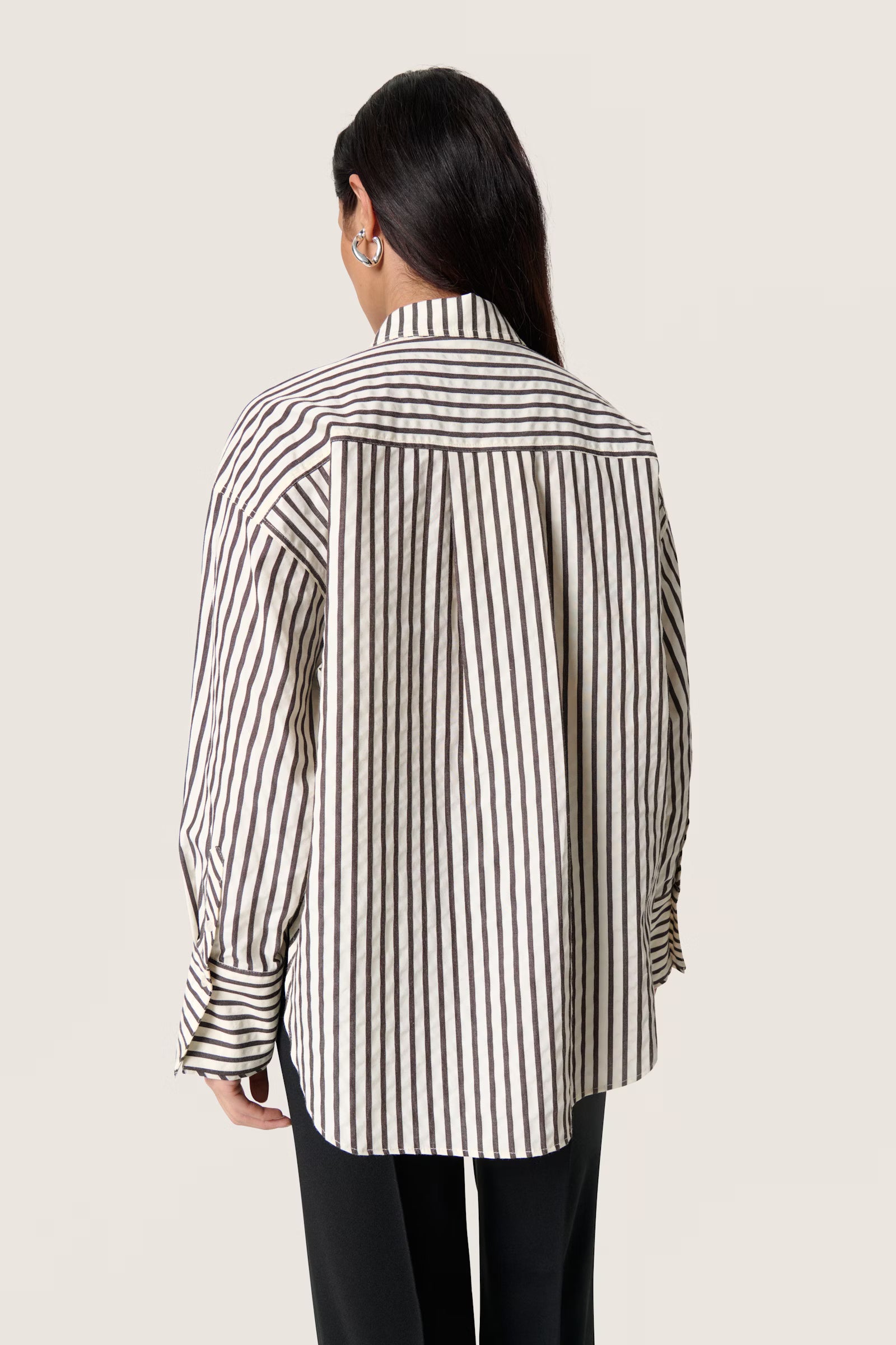 Person wearing a brown and white striped shirt on a plain background
