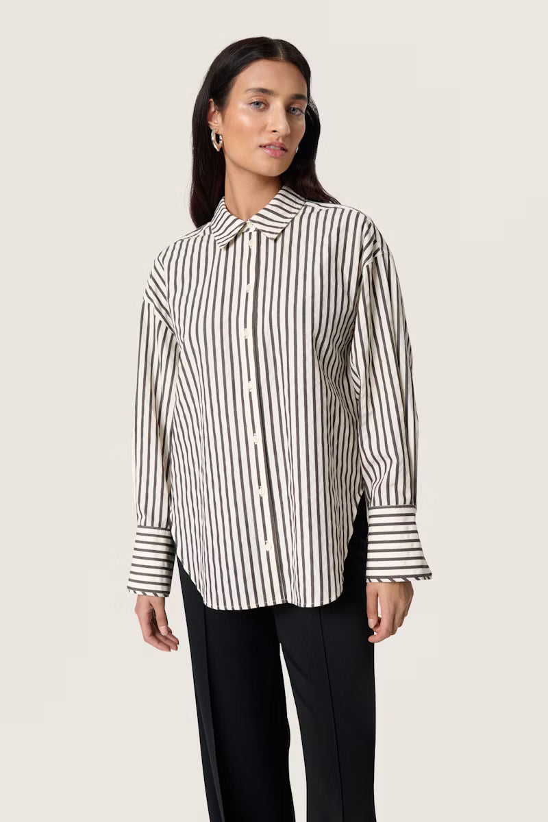 Woman wearing a brown and white striped shirt against a plain background