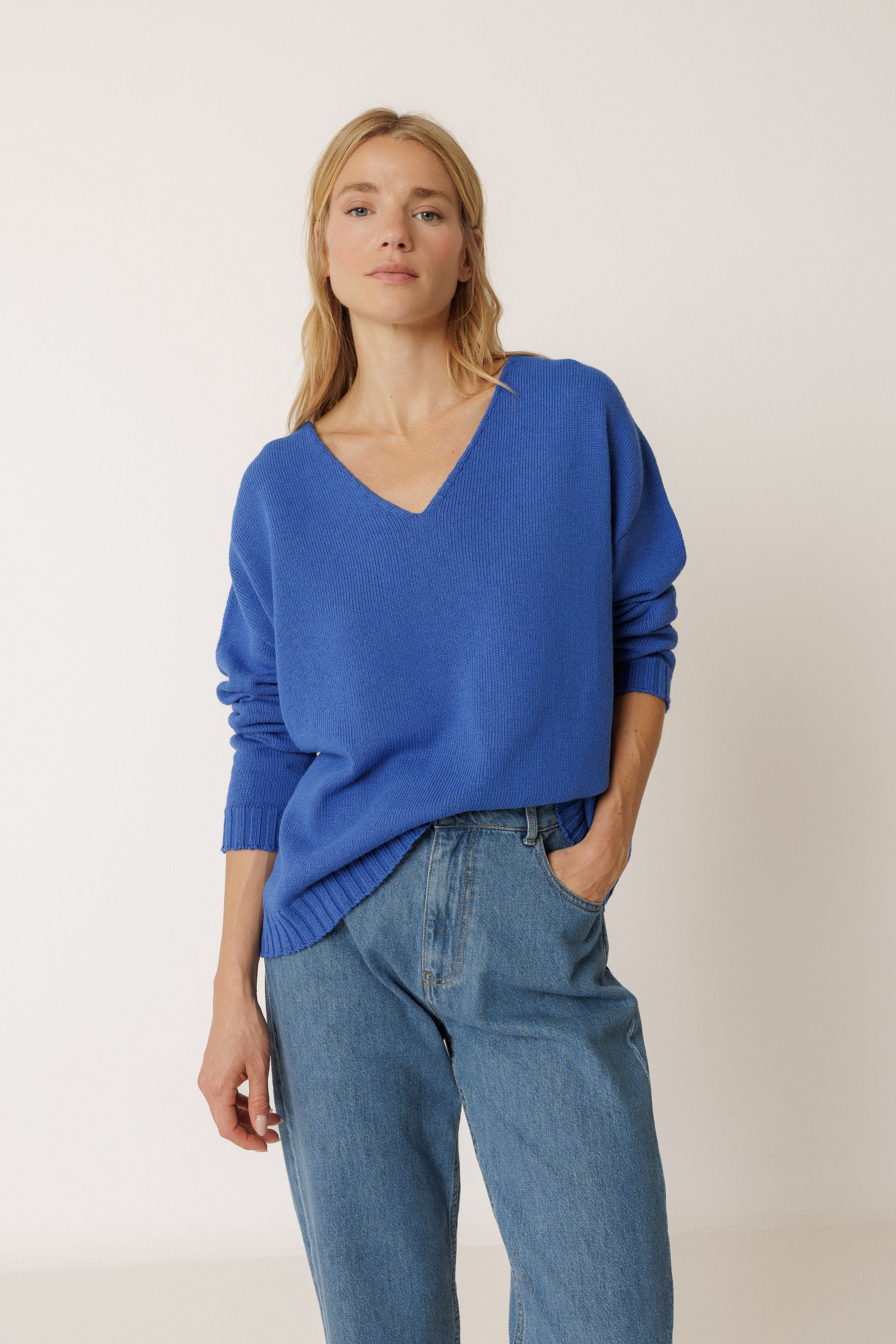 Woman wearing a blue sweater and jeans against a plain background