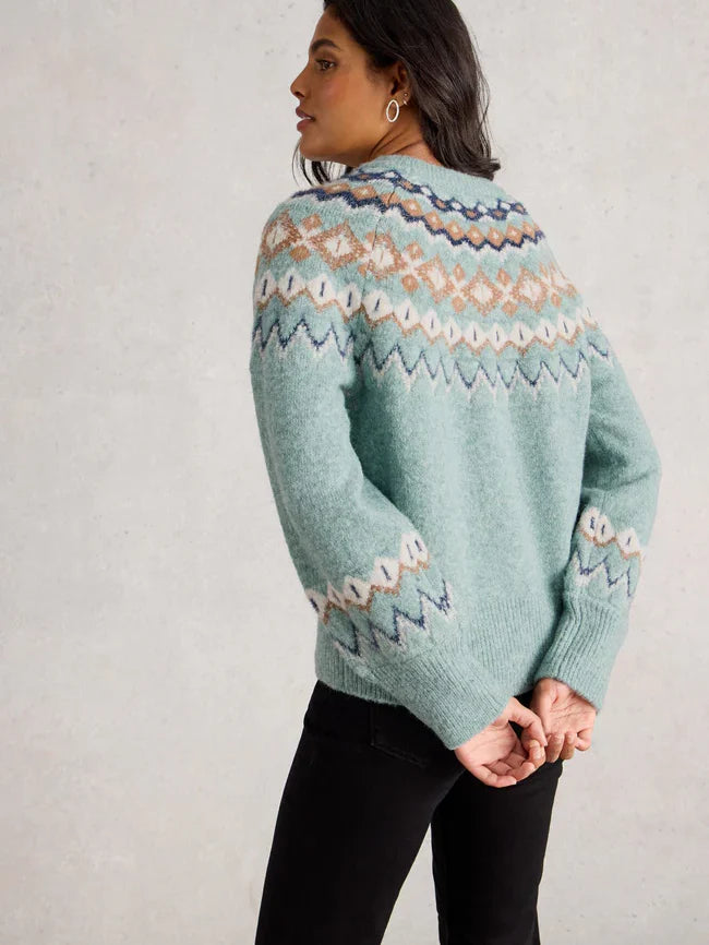 Person wearing a light blue knitted sweater with a pattern against a plain background