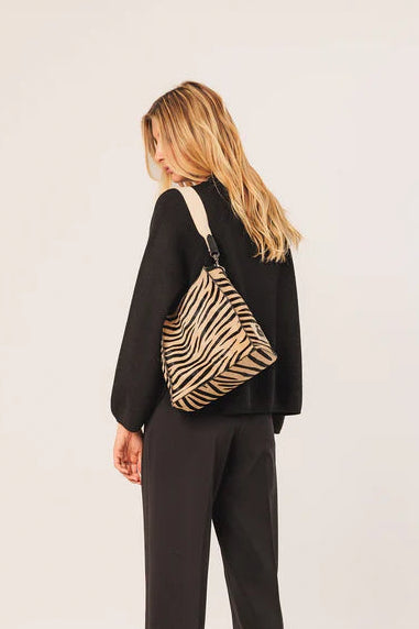 Person wearing a black outfit with a zebra-striped backpack on a white background